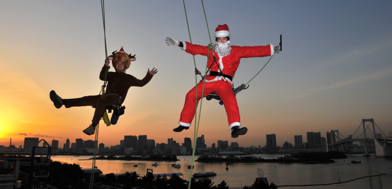 Trabajadores vestidos como  Santa Claus y Reindeer flotan en el aire mientras limpian los vidrios del edificio de un Shopping  a 31 metros de altura  en Tokio. AFP 