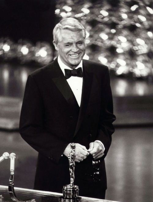 Cary Grant receiving an Academy Honorary Award in 1970 (online here)
&#8220;Years ago, when Cary Grant and Dyan Cannon were getting divorced, a perhaps apocryphal story appeared in the scandal sheets: As an example of Grant&#8217;s supposed irrationality, Cannon cited to the judge Cary&#8217;s yearly habit of sitting in front of his television and sardonically abusing all the participants. This item, true or not, must have amused nearly everyone in Hollywood, since nearly everyone in Hollywood does pretty much the same thing. 
The funny thing is that from all accounts, when the Academy Awards began in 1939, they were conducted in a similar spirit of irreverence, something that has practically disappeared from the event itself. &#8220;They used to have it down at the old Coconut Grove,&#8221; Jimmy Stewart told me in the late 70s. &#8220;You&#8217;d have dinner and alawta drinks - the whole thing was&#8230;it was just&#8230;it was a party. Nobody took it all that seriously. I mean, it was swell if ya won because your friends were givin&#8217; it to you, but it didn&#8217;t mean anything at the bawx office or anything. It was just alawta friends gettin&#8217; together and tellin&#8217; some jokes and gettin&#8217; loaded and givin&#8217; out some little prizes. My gawsh, it was..there was no pressure or anything like that.&#8221;
Cary Grant corroborated this to me: &#8221;It was a private affair, you see - no television, no radio, even - just a group of friends giving each other a party. Because, you know, there is something a little embarrassing about all these wealthy people publicly congratulating each other. When it began, we kidded ourselves: &#8216;All right, Freddie March,&#8217; we&#8217;d say, &#8216;we know you&#8217;re making a million dollars - now come up and get your little medal for it!&#8217;&#8221;
-excerpted from Peter Bogdanovich’s Who the Hell’s In It