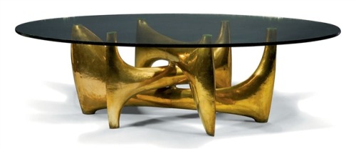This is the image that started our obsession. Philippe Hiquily is a French sculptor who draws inspiration from the female form. His work is overtly sexual and we find his furniture extremely sensual. He started designing furniture in 1960 about 20 years after he began his professional career.  The voluptuous curves of this dining table (c. 1968) harmonize with classical interiors while his use of hammered bronze, and aluminum adds gravitas to modern interiors. The tinted glass contributes a touch of whimsy and all together this design speaks of luxury, sultriness, ruggedness, abundance and playfulness.
It is a unique piece and was last sold at Christie’s Paris in 2010. Click on the image for lot details.
