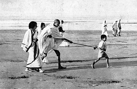 Gandhi conduzido por um garoto. Na praia, claro.
