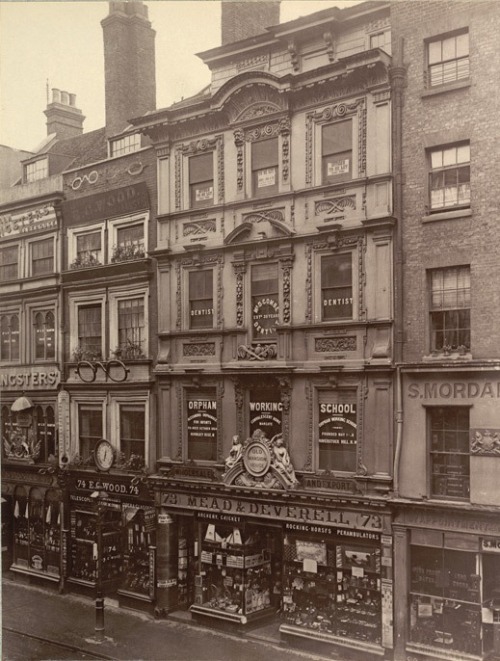 Cheapside, London, 1880: It&#8217;s fair to say that if a traveler from the 180&#8217;s was to arrive on Cheapside today, the only thing he would recognise would be St Mary-Le-Bow church. Gone are all the old buildings like these, replaced by tall cliff faces of beige concrete and dark glass. The 1880&#8217;s cheapside is a stark contrast to the plain thoroughfare of today; I could spend quite a while looking at the Victorian picture and come away still feeling as though there was something I&#8217;d missed, whereas if you were to look at a picture of modern-day Cheapside, there is, on the whole, nothing of great interest building-wise. A particular highlight for me on the 1880&#8217;s picture is, of course, Number 73. The ground floor of which is the shop Mead and Deverell. Zooming in reveals so much detail. Text above the shopfront windows advertises Rocking-Horses, Perambulators, what looks like Archery, and another word I can&#8217;t quite decipher. Above the shop is an Orphan Working School, above that is a dentist, and the very top floor is to let; I imagine there were many varied noises coming from that building&#8230; Next door on the left is E.G Wood, an optician. Unlike number 73, This business takes up the entire building, and has wonderful huge pairs of glasses both half way up, and right at the top of the building. A year before this photograph was taken Charles Dickens Junior wrote on Cheapside in his Dickens&#8217; Dictionary of London; &#8220;Cheapside remains now what it was five centuries ago, the greatest thoroughfare in the City of London. Other localities have had their day, have risen, become fashionable, and have sunk into obscurity and neglect, but Cheapside has maintained its place, and may boast of being the busiest thoroughfare in the world, with the sole exception perhaps of London Bridge.&#8221;