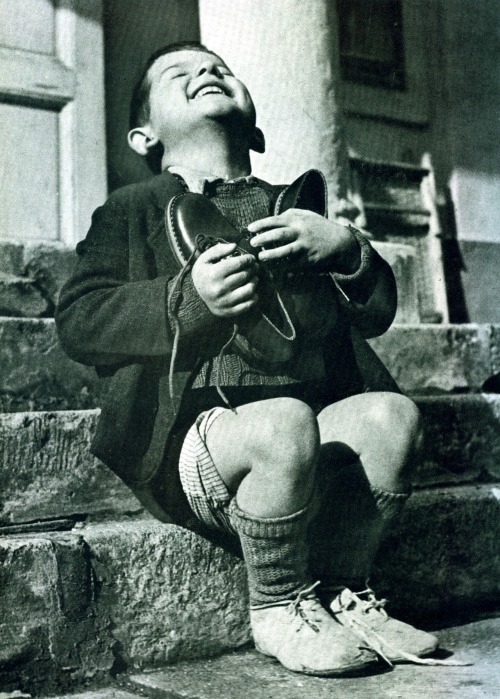Gerald Waller 
A New Possession: A six-year-old orphan from Austria (above) ecstatically embraces a brand-new pair of shoes just given to him by the Red Cross, 1946