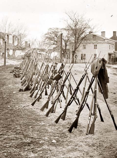 thecivilwarparlor:

Petersburg, Virginia Row of Stacked Federal Rifles
After the Battle of Gettysburg, the discarded rifles were collected and sent to Washington to be inspected and reissued.
 Of the 37,574 rifles recovered, approximately 24,000 were still loaded; 6,000 had one round in the barrel; 12,000 had two rounds in the barrel; 6,000 had three to ten rounds in the barrel. One rifle, the most remarkable of all, had been stuffed to the top with twenty-three rounds in the barrel.

