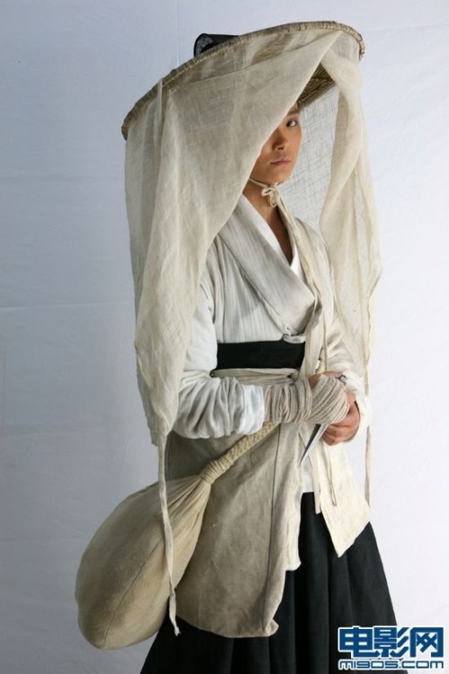 The first photo shows an Asian peasant woman wearing off-white clothing and a hat. A veil hangs from the edge of the hat. The left side of the woman, which is to your right, can be seen peeking from an opening of the veil. The bottom right of the photo credits the photo to the web site m1905.com.