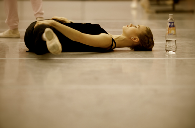 Ballet dancer straddle stretches on the floor